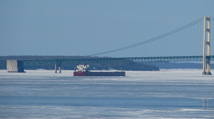 Freighter passing under the Mackinac Bridge in winter.