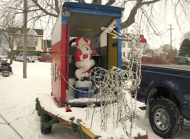 Santa Claus in an outhouse pulled by reindeer.
