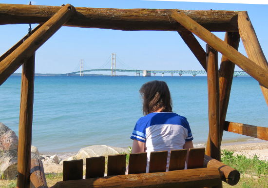 Linda on a swing looking out at the Straits of Mackinac and the Mighty Mac - Mackinac Bridge
