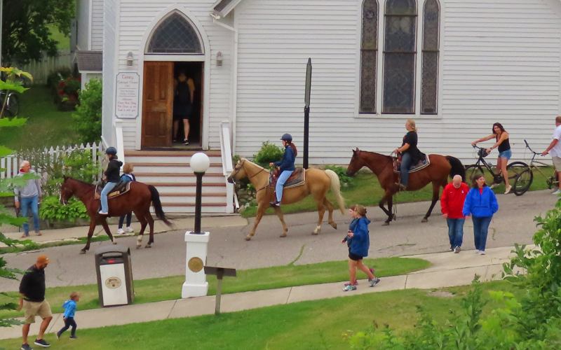 Trinity Episcopal Church and horse back riders on Mackinac Island