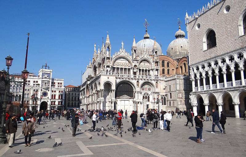 People feeding the pigeons in front of the Basilica of Saint Mark.